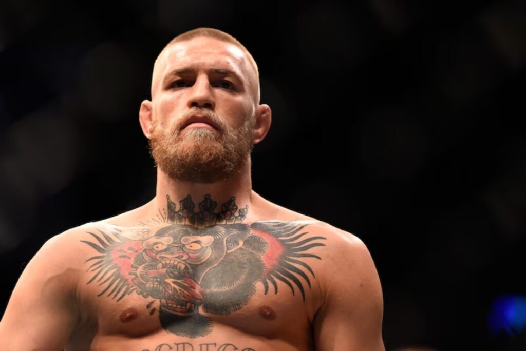 El luchador de la UFC Conor McGregor mira a la cámara con expresión seria, mostrando sus tatuajes en el pecho y el cuello.