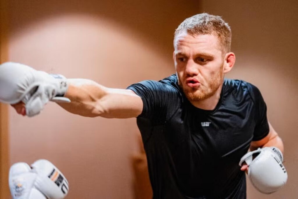 A focused Jack Della Maddalena in a black shirt and white gloves throws a punch during a training session.
