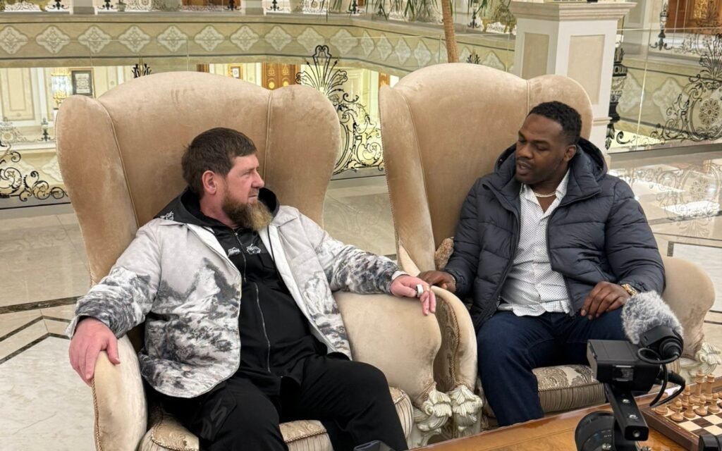 Jon Jones y Ramzan Kadyrov sentados en sillones ornamentados, conversando en un salón lujoso.