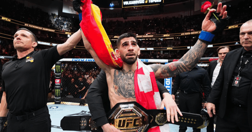 Ilia Topuria, emocionado, celebra con el cinturón de campeón de UFC y la bandera de España tras su victoria.