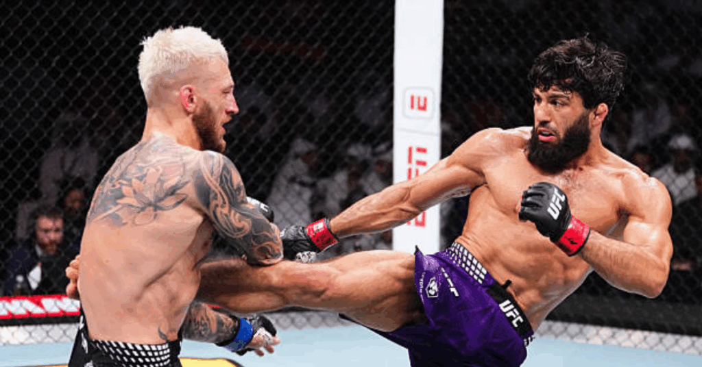 Un luchador de la UFC lanza una patada al cuerpo de su oponente de pelo rubio en el octágono.