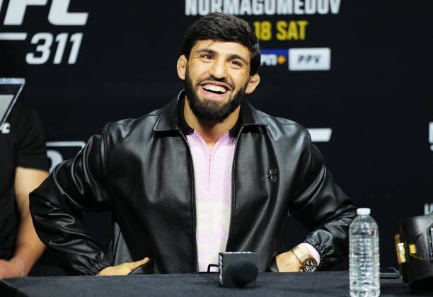 El peleador de UFC Umar Nurmagomedov sonríe con una chaqueta de cuero negra en una conferencia de prensa.