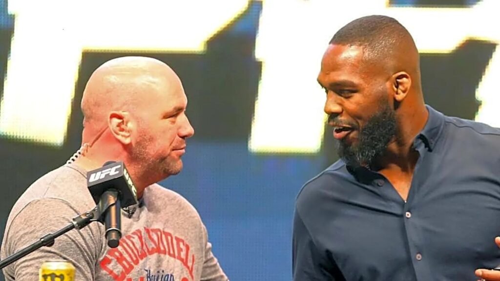 UFC President Dana White and fighter Jon Jones stand face-to-face, engaged in a conversation at a media event.
