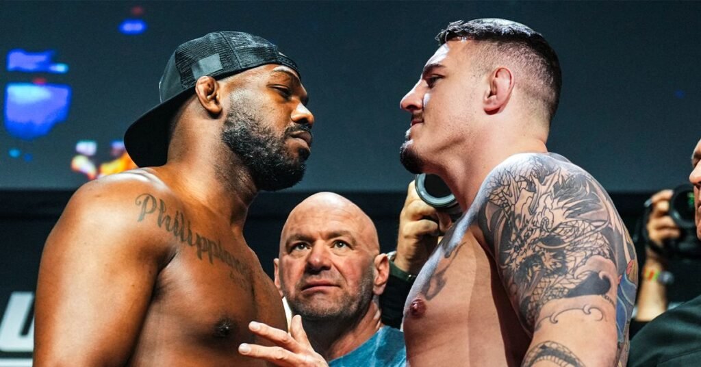 Jon Jones and Tom Aspinall in an intense UFC faceoff with Dana White looking on between them.