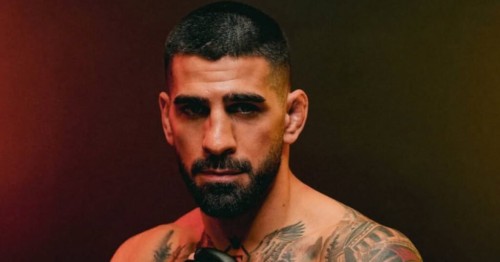 Ilia Topuria, luchador barbudo de MMA con pelo corto y oreja de coliflor, mirada intensa, mostrando tatuajes en hombros.