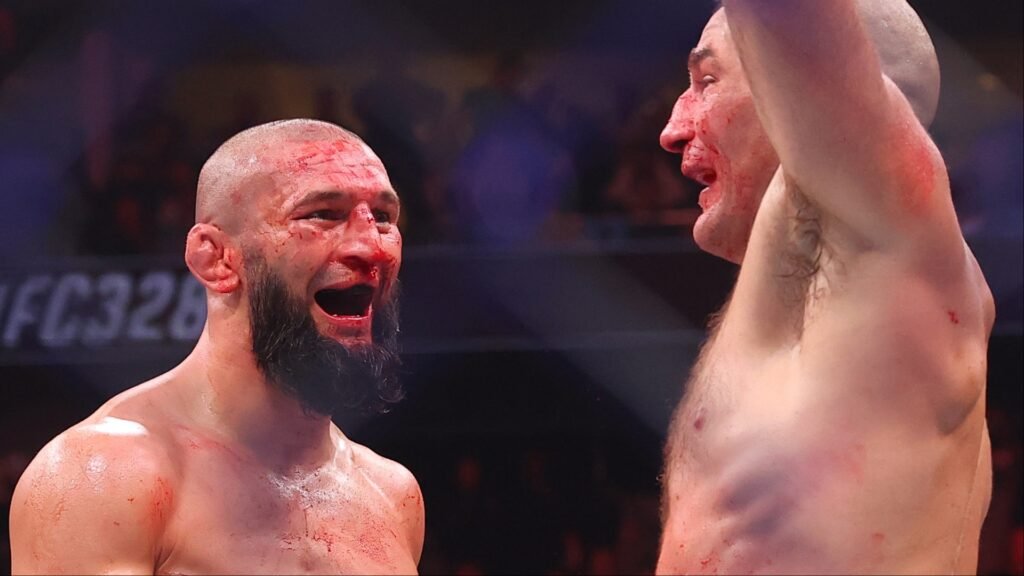 Dos luchadores de UFC ensangrentados post-combate. Uno con barba grita, el otro celebra la victoria alzando el brazo.