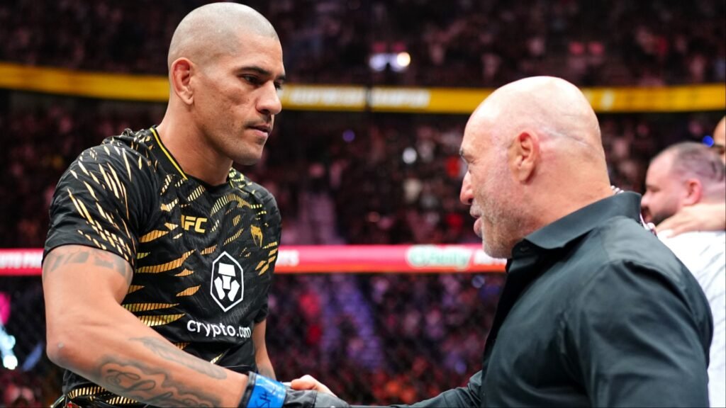 Alex Pereira, con camiseta UFC negra y dorada, estrecha la mano de un hombre barbudo y calvo en el octágono.