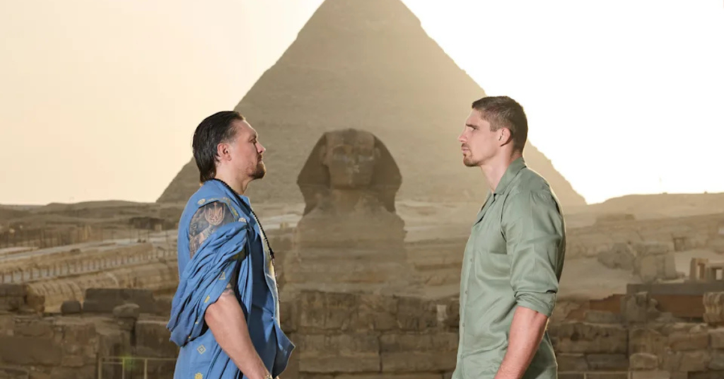 Careo de dos boxeadores: uno con túnica azul, otro con camisa verde, frente a la Esfinge y la Pirámide de Giza, Egipto.