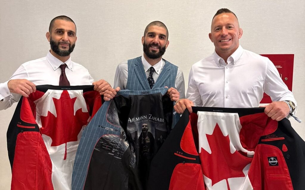 Tres hombres sonríen, mostrando forros de chaqueta personalizados. Dos con bandera canadiense; uno de Aiemann Zahabi 'King of the North'.
