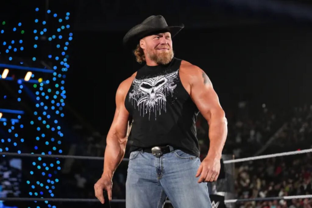 Brock Lesnar, musculoso luchador de WWE, con barba, sombrero vaquero y camiseta de calavera, sonriendo en SmackDown.