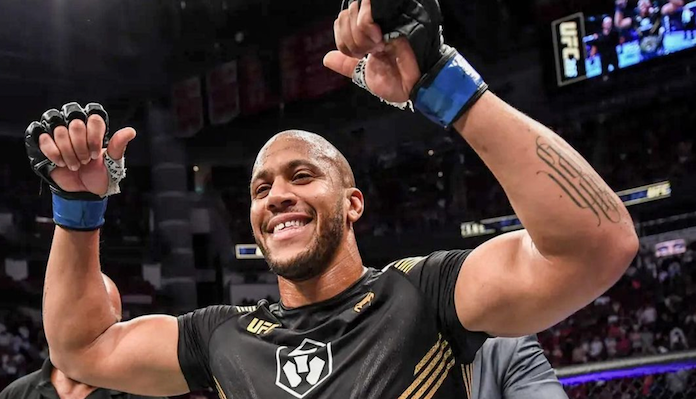 Luchador de MMA sonriente y musculoso celebrando con brazos en alto y pulgares arriba en un evento UFC.