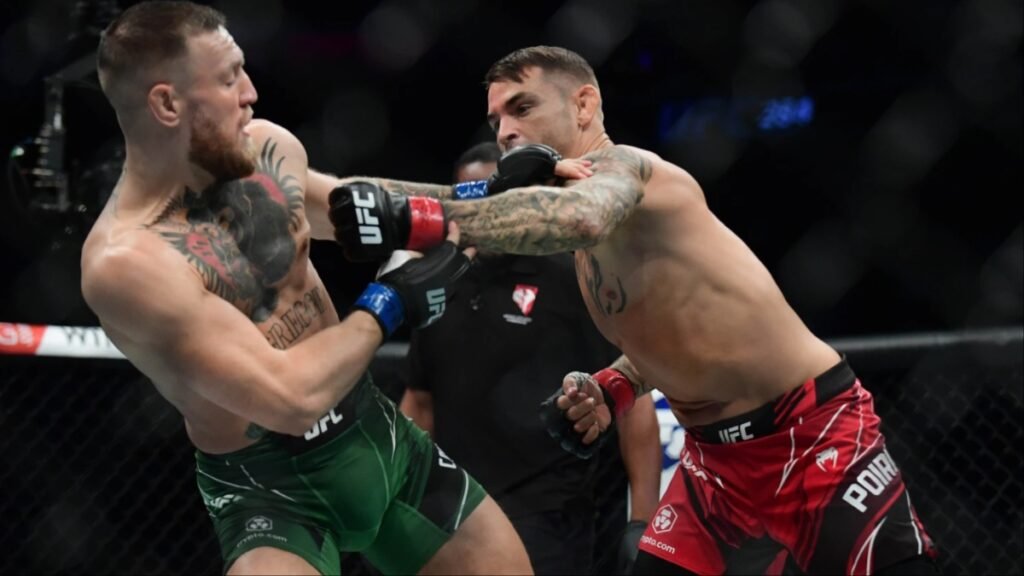 Conor McGregor (pantalones verdes) y Dustin Poirier (pantalones rojos) lanzan golpes en un combate de UFC en el octágono.