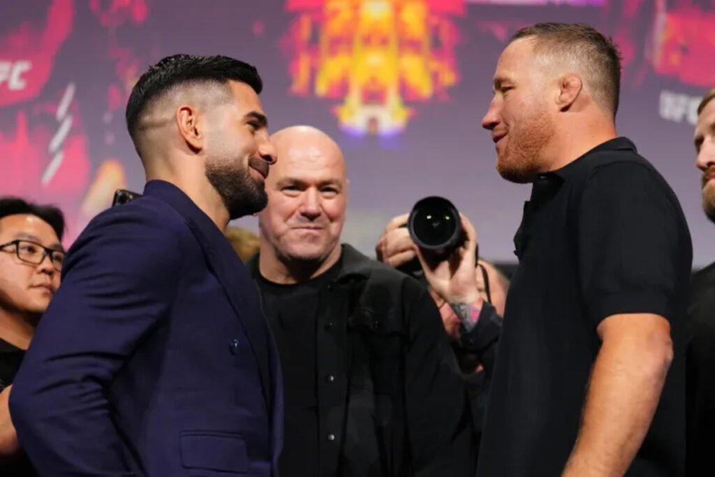 Cara a cara intenso de UFC: Ilia Topuria y Justin Gaethje se miran fijamente, con Dana White observando en el fondo.