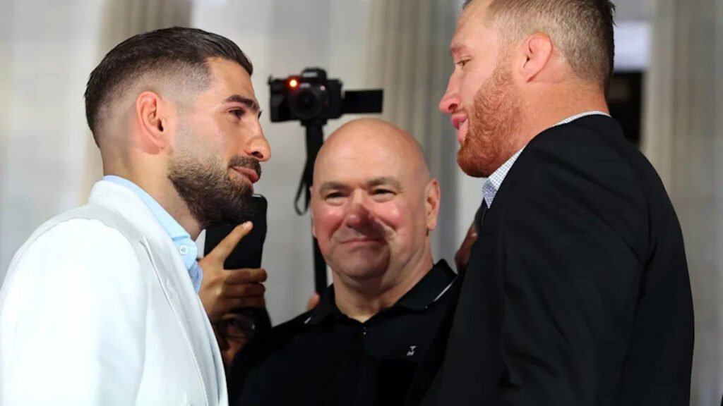 Intenso careo UFC entre Ilia Topuria (chaqueta blanca) y Justin Gaethje (traje negro). Dana White sonríe al fondo.