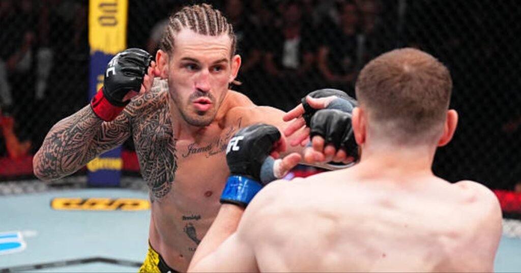 Luchador de UFC con trenzas y tatuajes tribales en los brazos lanza un golpe potente. Otro combatiente de espaldas en el octágono.