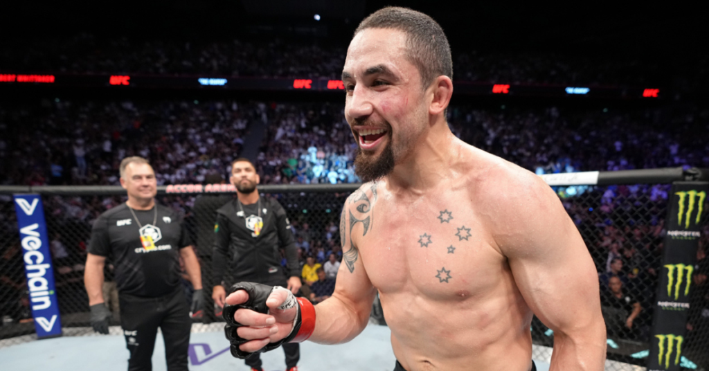 Robert Whittaker sonríe victorioso en el octágono de la UFC, mostrando sus tatuajes de la Cruz del Sur.