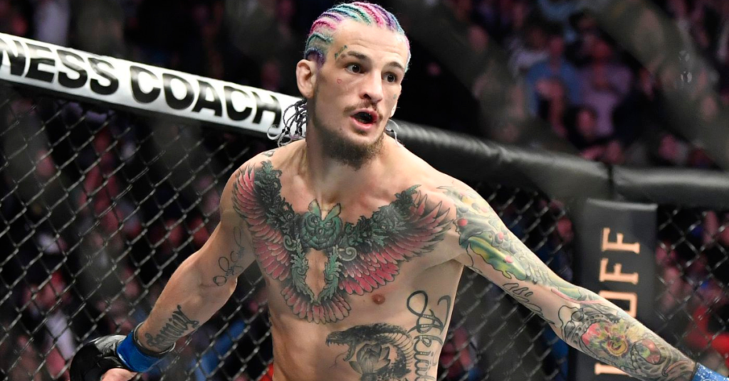 Sean O'Malley, peleador de UFC, con pelo trenzado de colores y tatuajes de un búho y una serpiente, en la jaula.