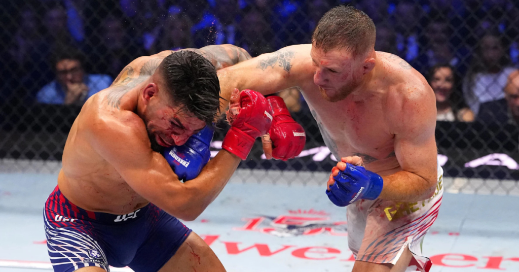 Lucha de MMA: un púgil con guante rojo golpea ferozmente la cara ensangrentada de su oponente en el octágono.