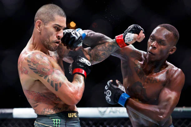 Alex Pereira (tatuado) asesta un puñetazo a Israel Adesanya en un combate de UFC. Intensa acción de MMA.