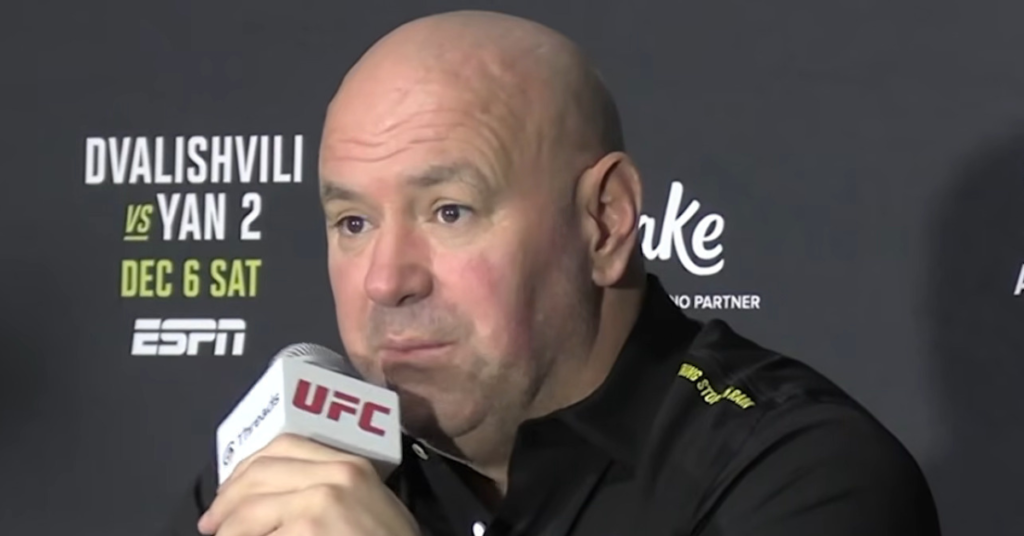 Dana White, calvo, con micrófono UFC en rueda de prensa. De fondo, cartel de Dvalishvili vs Yan 2, DEC 6 SAT y ESPN.