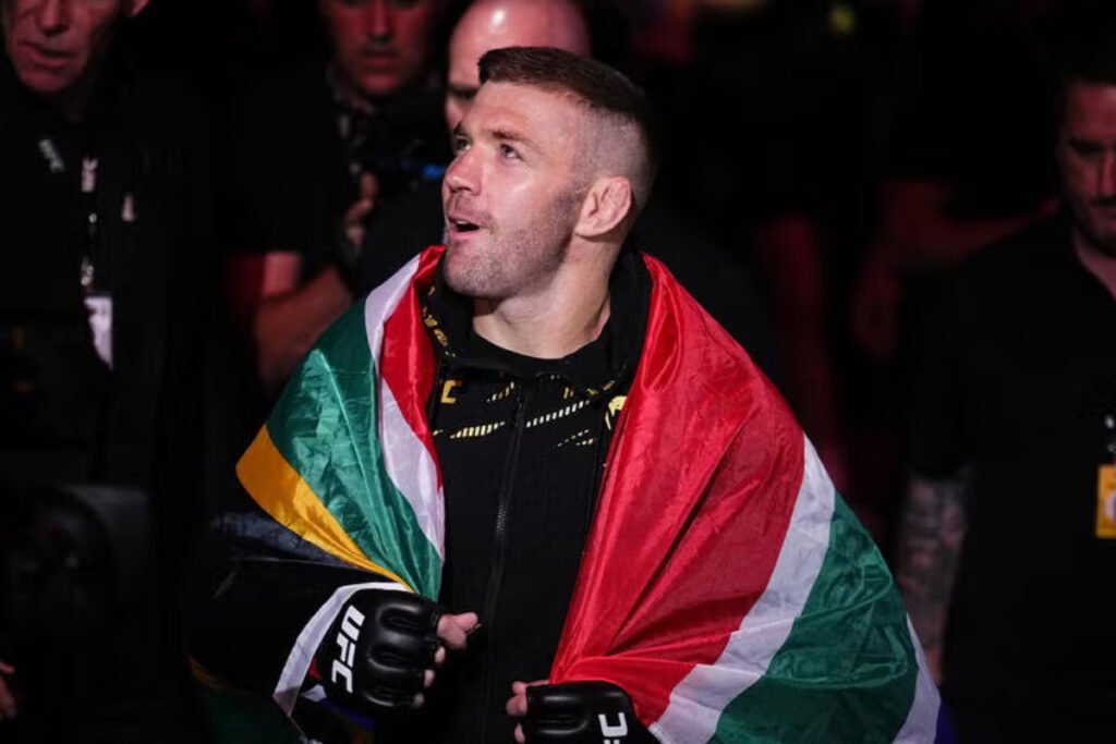 Luchador de UFC sudafricano envuelto en la bandera de Sudáfrica, con guantes de combate negros.