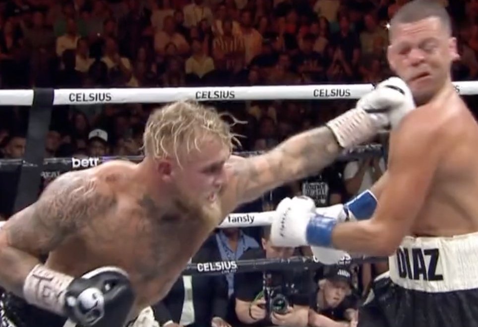 Jake Paul asesta un puñetazo a Nate Diaz en un combate de boxeo. La cara de Diaz se deforma por el impacto en el ring.