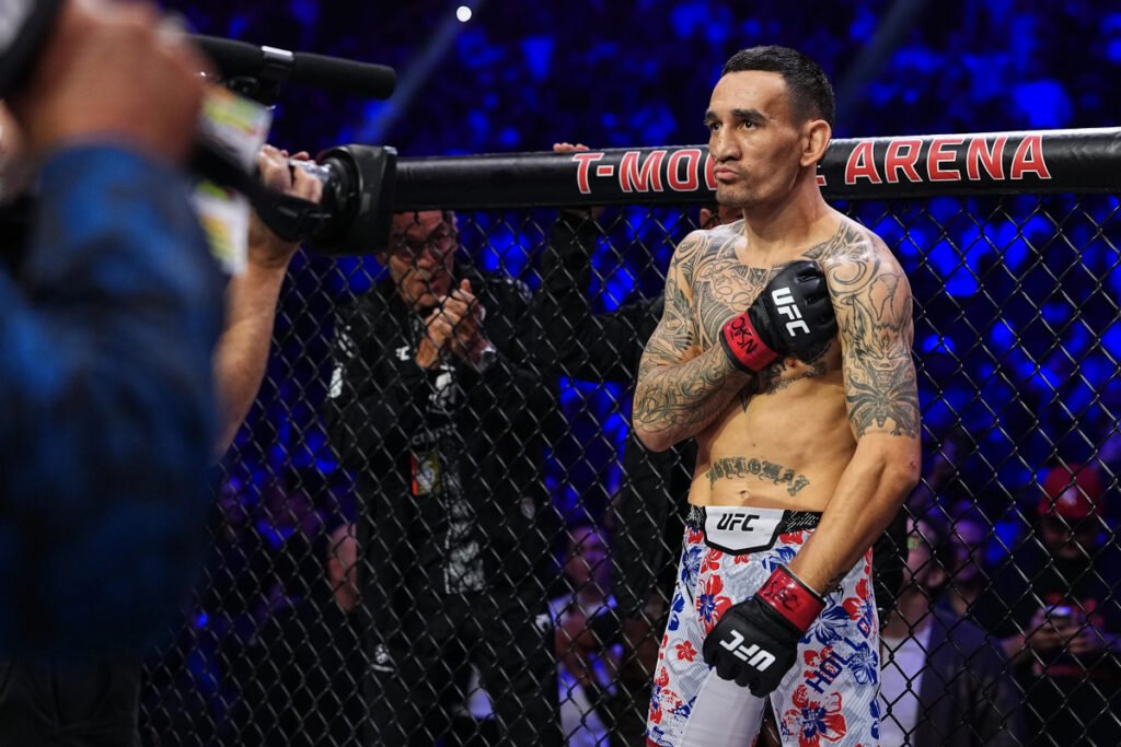 Max Holloway, luchador de UFC tatuado, en el octógono de la T-Mobile Arena. Lleva guantes, con la mano al pecho, antes de la pelea.