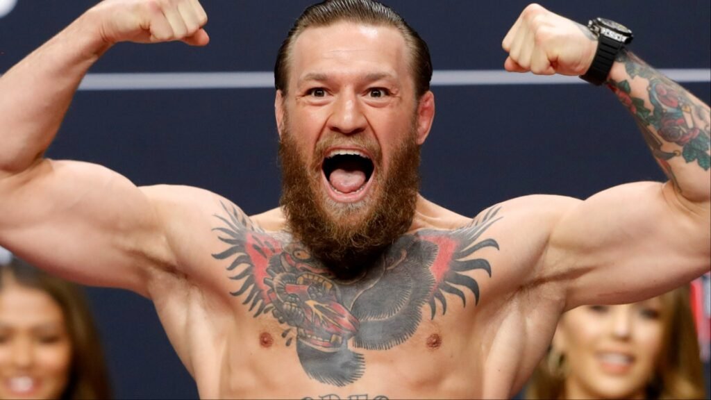 Conor McGregor, luchador de la UFC, grita y flexiona sus bíceps. Luce su icónico tatuaje de gorila en el pecho y manga en el brazo.