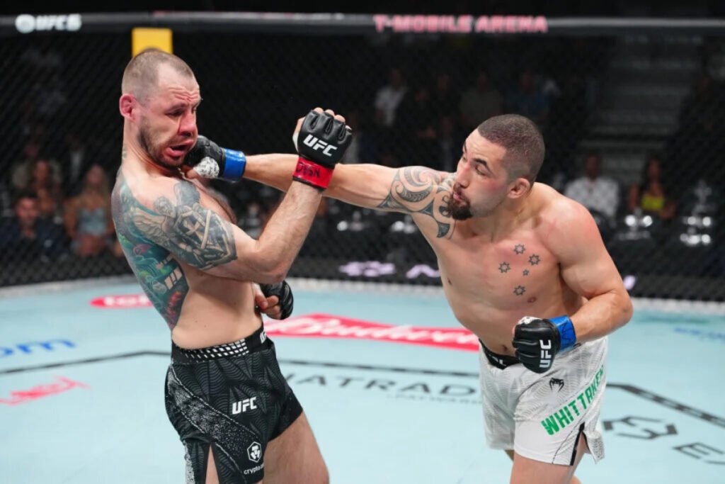 Robert Whittaker conecta un potente puñetazo a la cara de su rival en UFC, que reacciona con el rostro visiblemente deformado.
