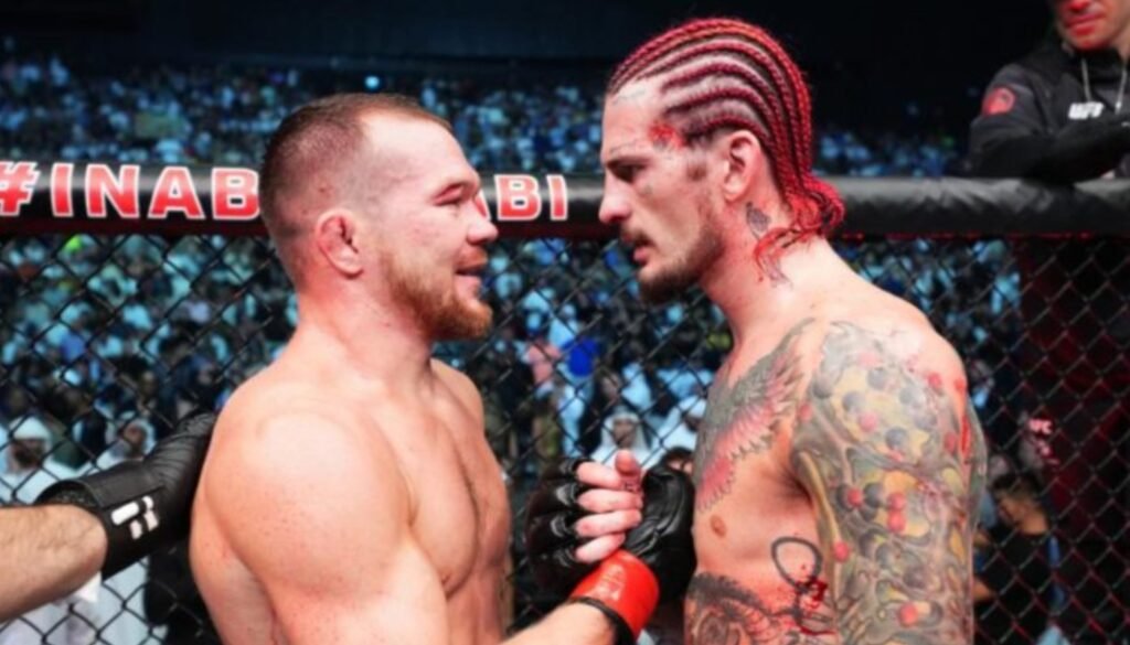 Luchadores de UFC Sean O'Malley (trenzas rojas) y Petr Yan se encaran intensamente en el octágono antes de su combate.