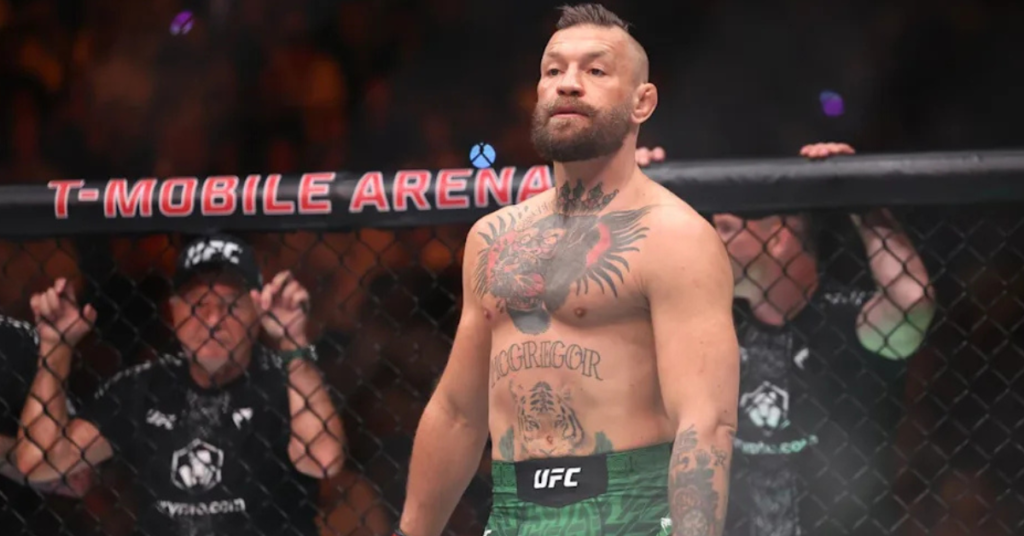 Conor McGregor en el octágono de la T-Mobile Arena, luciendo tatuajes en pecho y abdomen, y pantalones cortos verdes UFC.