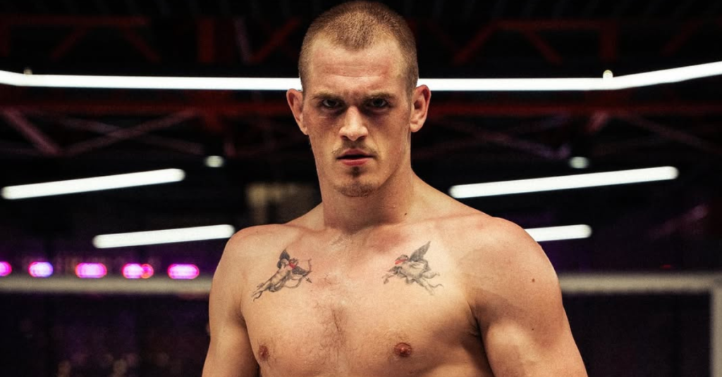 Luchador de MMA con intensa mirada, torso musculoso y tatuajes de querubines en el pecho, listo para combatir en la arena.