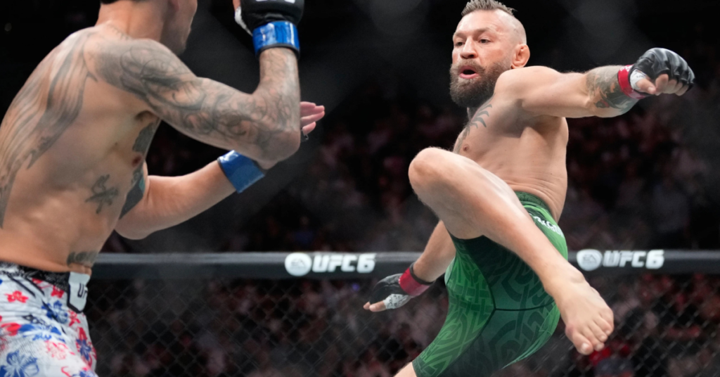 Conor McGregor lanza un rodillazo volador en un combate de UFC. Su oponente, con tatuajes en el torso, bloquea o esquiva.