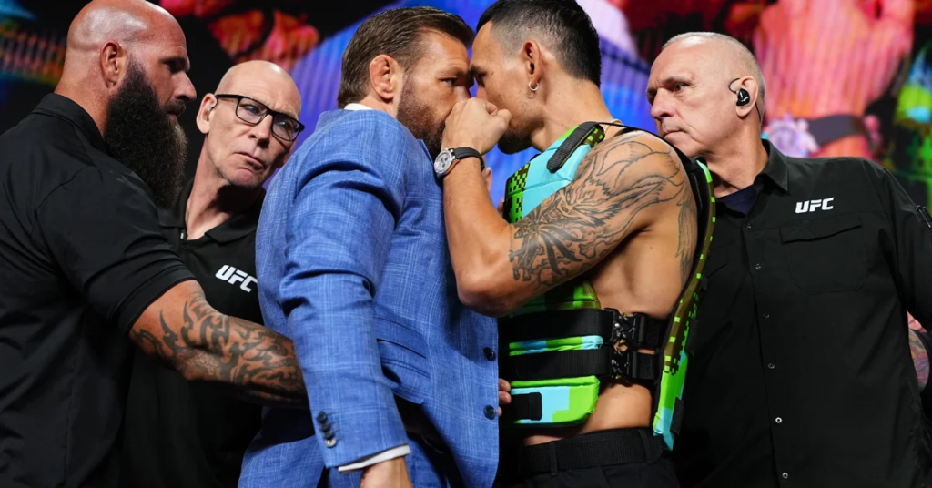 Intenso careo de UFC. Dos luchadores se encaran, separados por árbitros y personal de seguridad. Uno viste traje, el otro un chaleco.