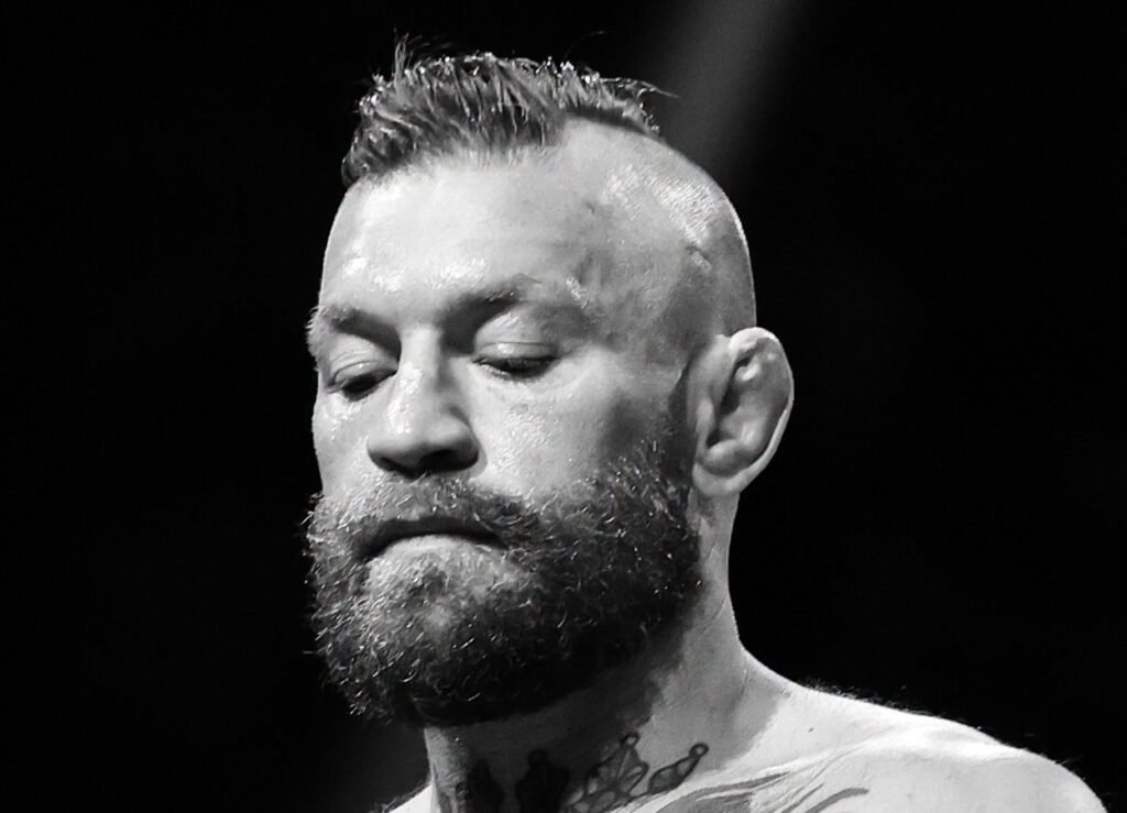Conor McGregor, luchador de MMA, sudoroso y concentrado. Luce barba, cresta, oreja de coliflor y tatuajes en blanco y negro.