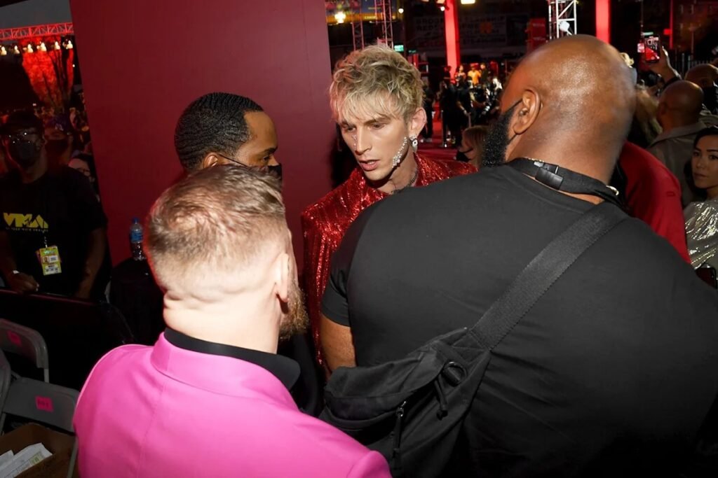 Machine Gun Kelly con chaqueta roja de lentejuelas y Conor McGregor con americana rosa interactuando en los VMA.