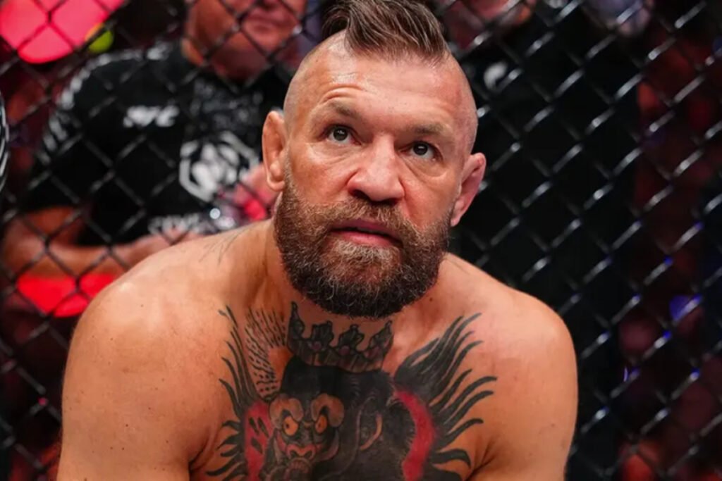 Conor McGregor, luchador de UFC, con barba y tatuajes, mira sorprendido tras una lesión en el octágono.