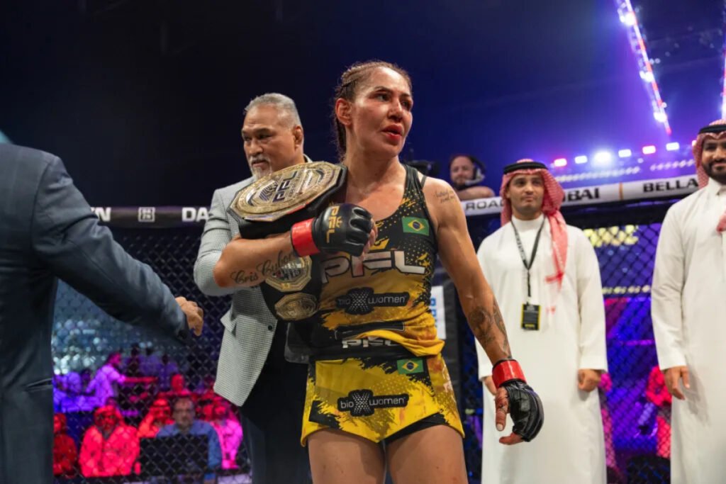 Cris Cyborg, campeona de MMA PFL, luce el cinturón tras la pelea. Cara marcada, hombres con vestimenta árabe en Dubái.