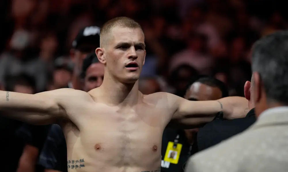 Luchador de UFC Ian Machado Garry sin camiseta, brazos extendidos en el pesaje ante el público.