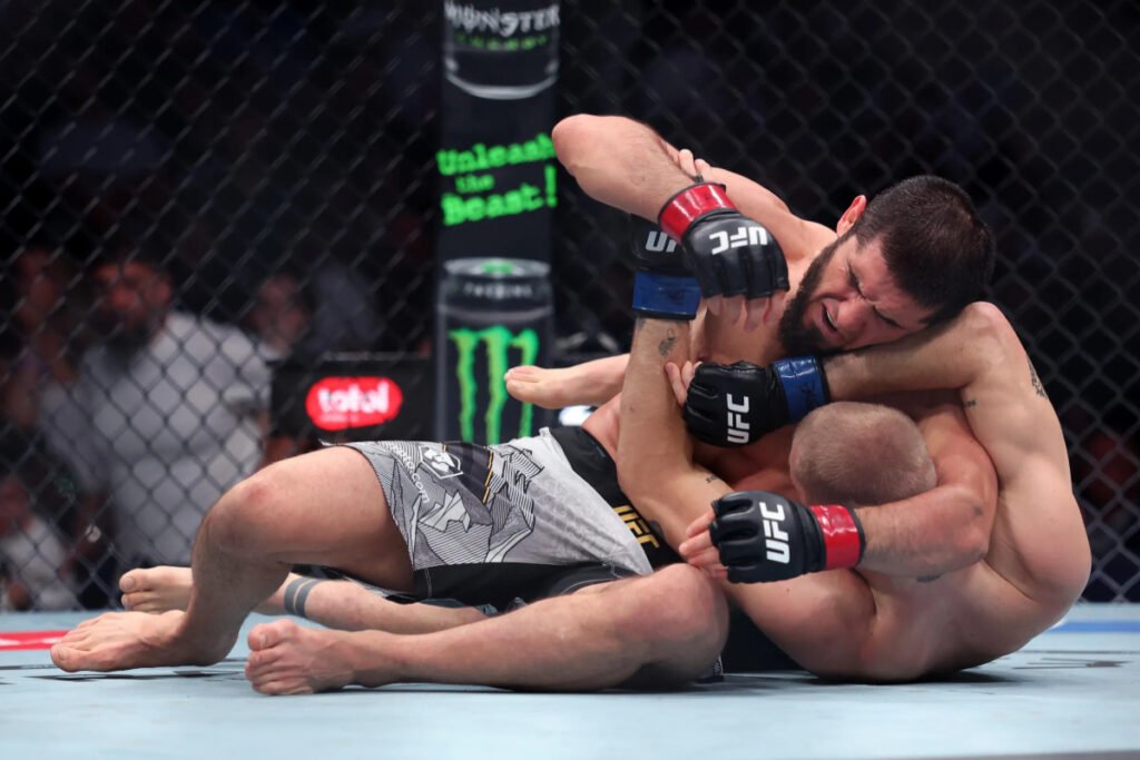 Islam Makhachev somete a Ian Machado Garry en UFC 330, un intenso combate de MMA en la jaula.