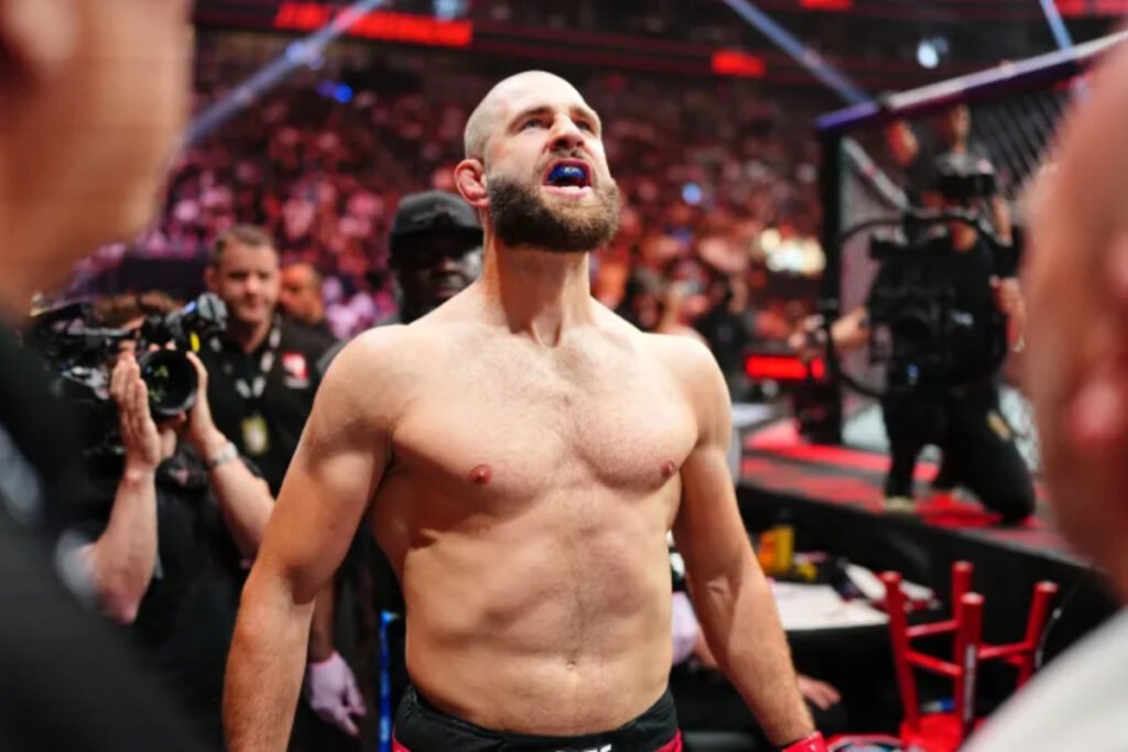 Jiri Prochazka, luchador de UFC calvo y barbudo, mira arriba con protector bucal azul en la arena.