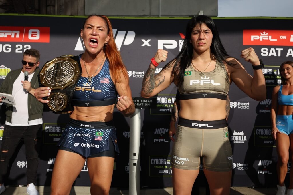 Dos luchadoras de MMA, Cris Cyborg con cinturón y Ketlen Vieira flexionando brazos, en pesaje PFL.