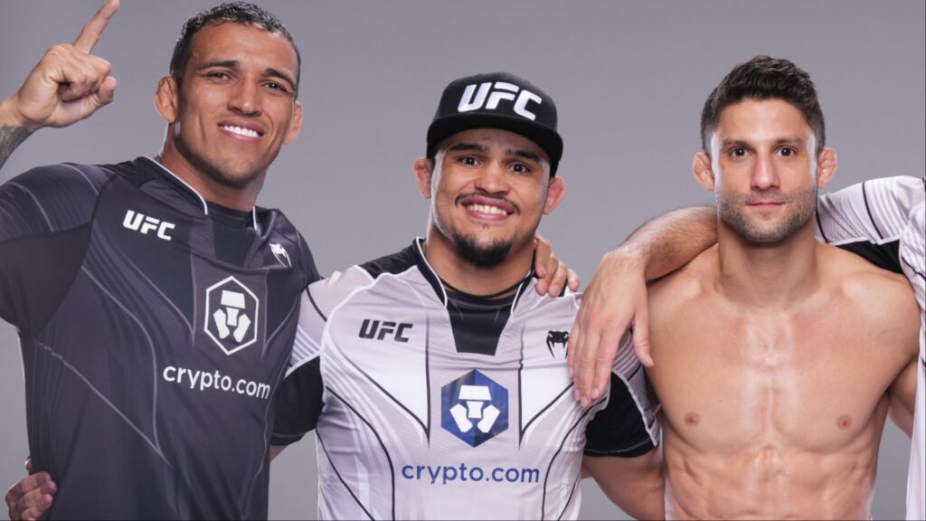 Luchadores UFC Charles Oliveira, Ilia Topuria (con gorra y camiseta Crypto.com) y Mateusz Gamrot (torso desnudo) sonríen.