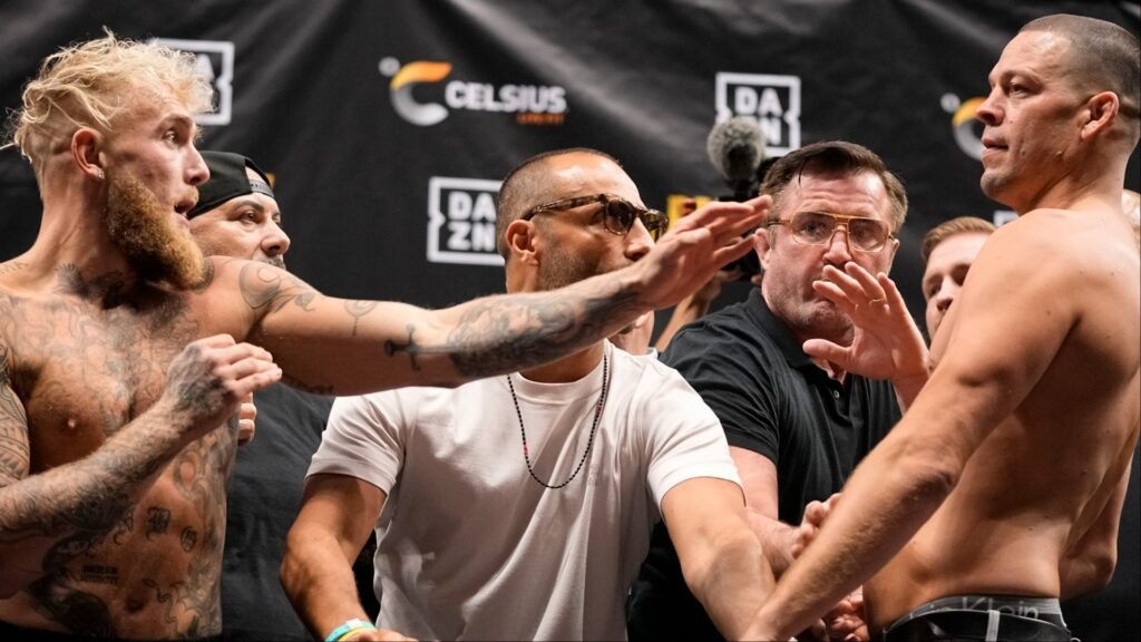 Jake Paul y Nate Diaz, sin camiseta, en un tenso cara a cara del pesaje. Un oficial los separa frente a logos de Celsius y DAZN.