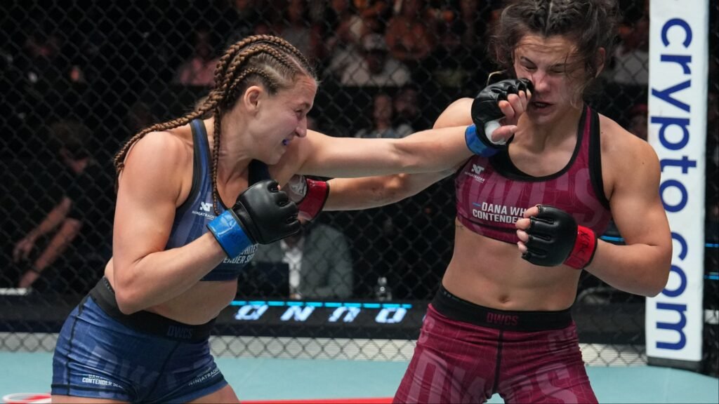 Puñetazo de luchadora de MMA con trenzas a la cara de su rival en combate intenso dentro de la jaula.