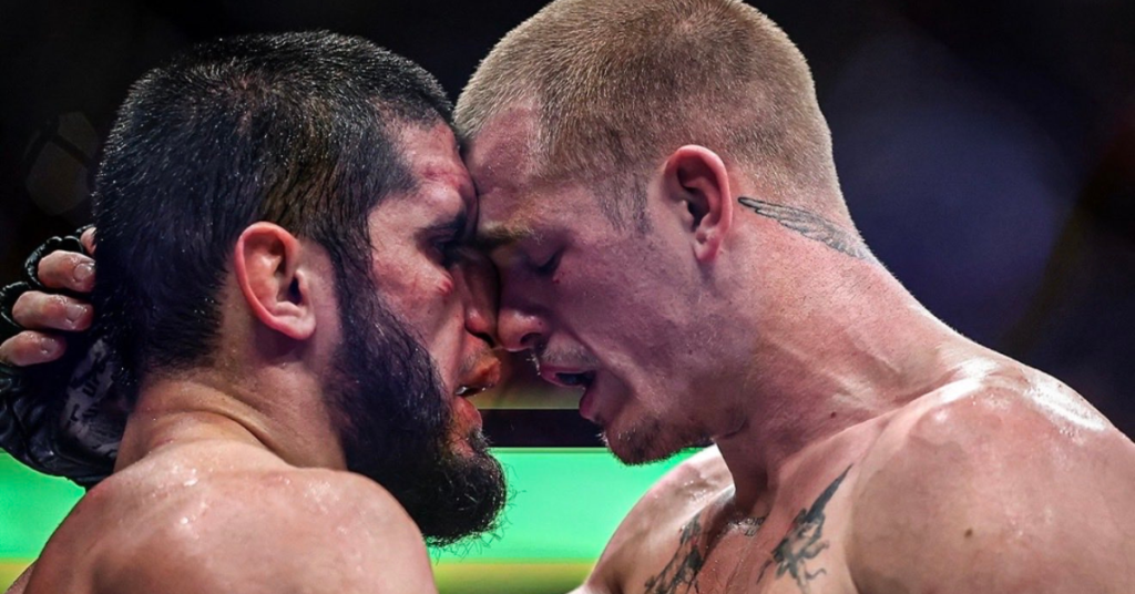Luchadores de MMA sudorosos, uno barbudo y el otro rubio, frente a frente en el ring tras un intenso combate.