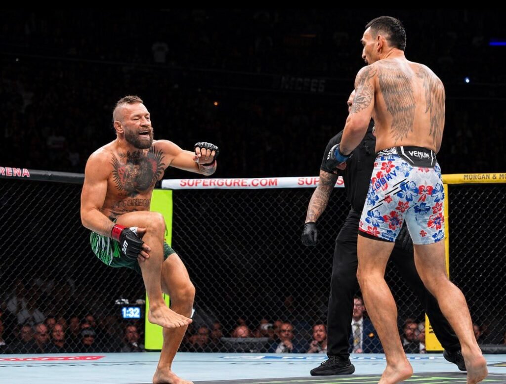 Combate UFC: Conor McGregor, tatuado y expresivo, levanta la pierna ante Tony Ferguson y un árbitro en el octágono.