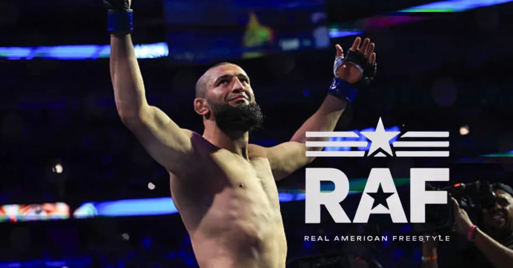 Khamzat Chimaev, luchador musculoso y barbudo, celebra con brazos alzados en una arena. Logo RAF Real American Freestyle.