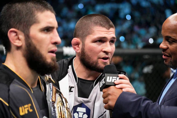 Islam Makhachev, campeón UFC con cinturón, junto a Khabib Nurmagomedov, entrevistados por Daniel Cormier.