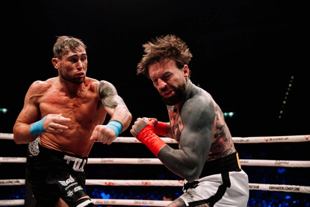 Darren Till y Aaron Chalmers en un tenso combate de BKFC a puño limpio. Ambos luchadores muestran gran esfuerzo en el ring.